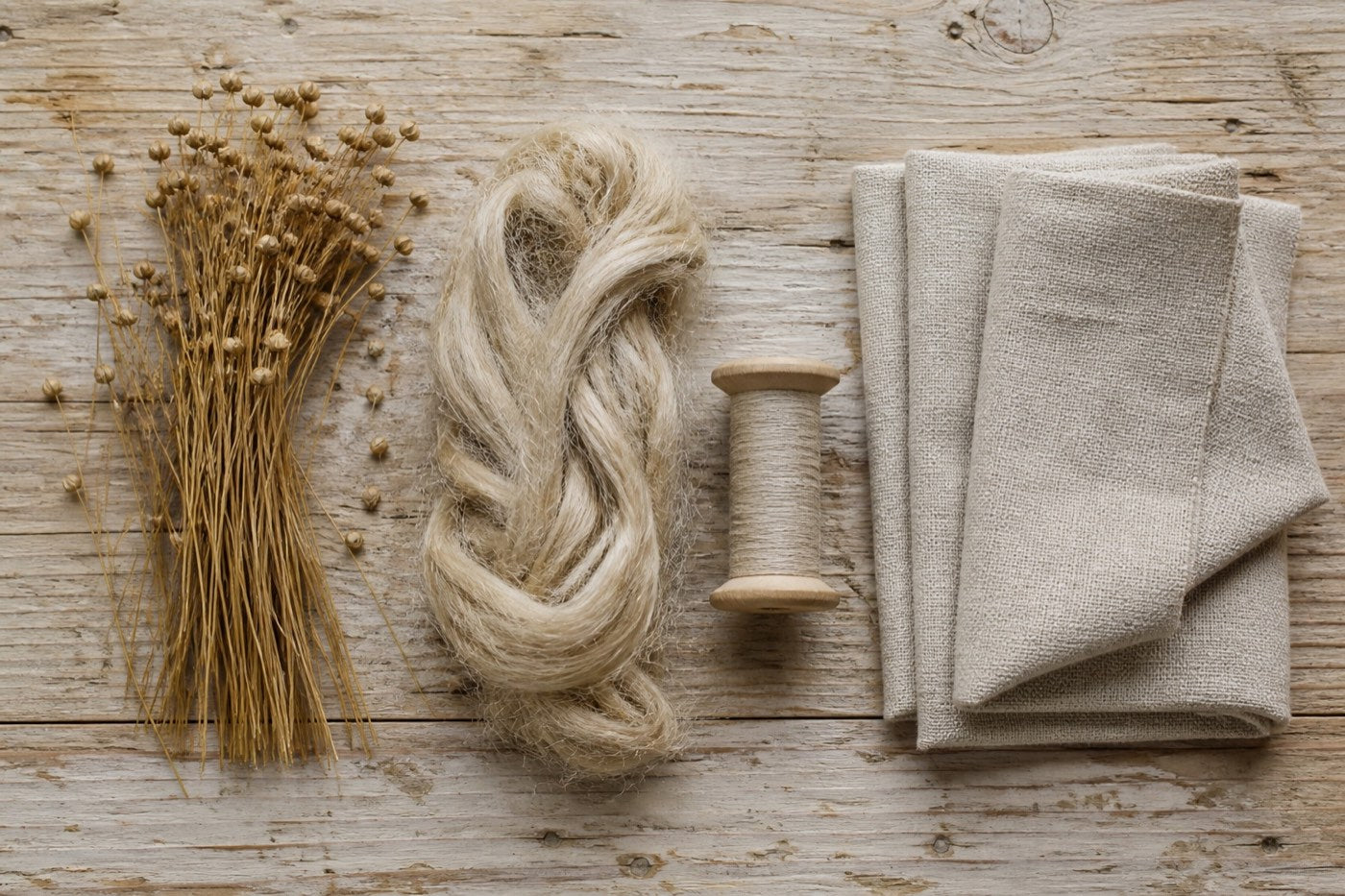 Flax stems, combed fibre, linen thread and woven cloth arranged in sequence